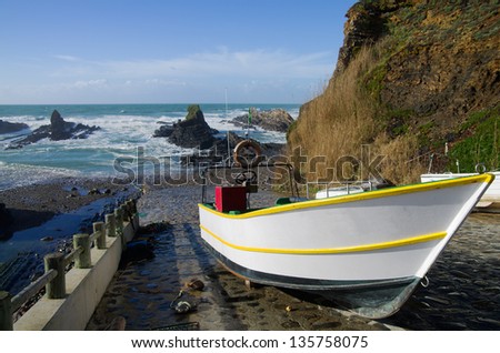 Small fishing boat out of water at traditional fishing harbour of Lapa de Pombas. Focus on boat. Almograve, Portugal.