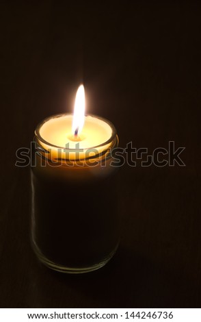 Craft candle made of wax inside a glass jar lit in the dark.