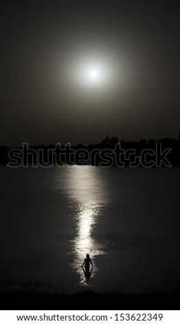 Naked Woman Silhouette Entering Lake Water In The Reflection Of The