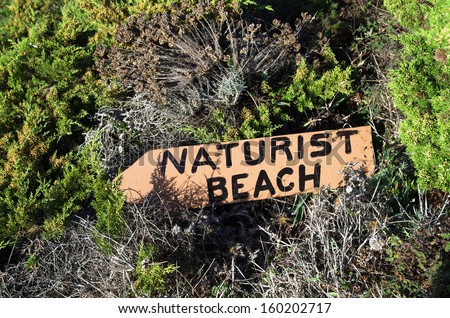 Naturist beach sign lost in the middle of the vegetation.