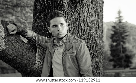 Black and white portrait of handsome young man and tree