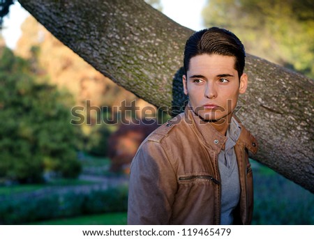 Handsome young guy in fall (autumn) outdoors in nature, at dusk