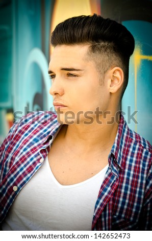 Profile of handsome young man against colorful graffiti covered wall