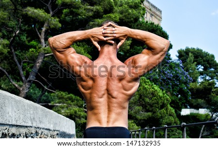 Muscular bodybuilder with hands behind his head showing back, shoulders and arms