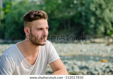 Portrait of handsome young man outdoors in nature, looking to a side