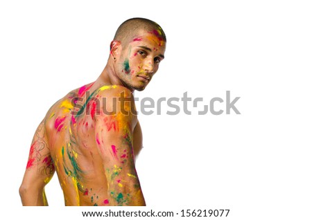 Attractive young man shirtless, skin painted all over with bright colors seen from behind