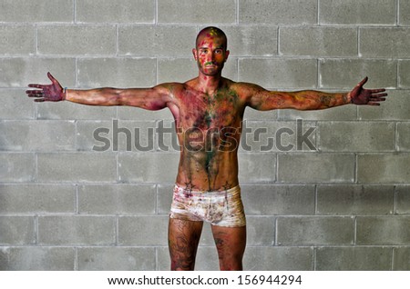Handsome young man with skin all painted with colors, arms spread open