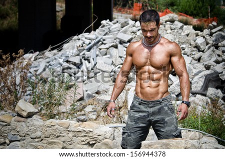 Muscle man shirtless outdoors in building site. Construction worker