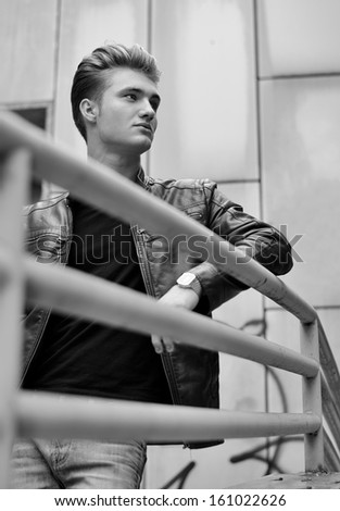 Handsome blond haired young man on metal railing, black and white shot