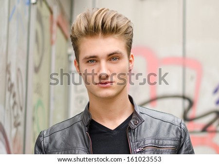Head shot of handsome blond young man, outdoors looking in camera