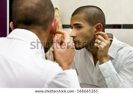 Handsome young man touching and examining his ear piercings