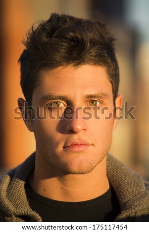 Headshot of handsome young man, lit by sunset light