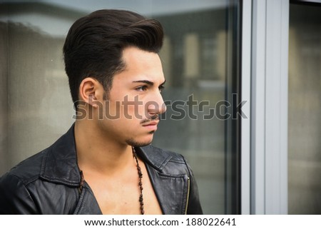 Handsome young man with leather jacket looking away outdoors