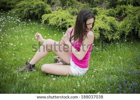 Attractive young woman on grass scared or frightened by insects and bugs
