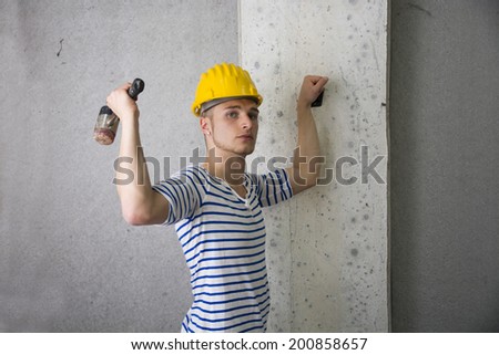 Handsome construction worker with yellow hard hat and hammer in hand