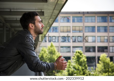 Profile  shot of attractive bearded young man in city, looking afar outdoors