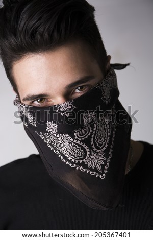 Man with his face hidden behind a bandanna stares balefully at the camera
