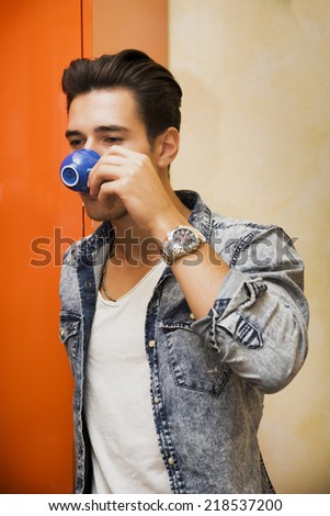 Young Man Drinking from Blue Espresso Coffee Cup as if On the Go