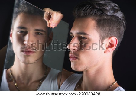 Narcissistic handsome young man admiring his reflection in the mirror in a show of self-absorption