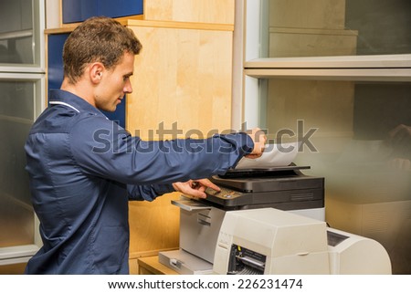 Young Handsome Man Operating High-Tech Photocopier Machine at the Office.