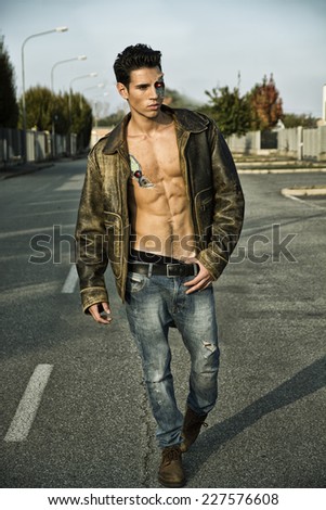 Young Handsome Robotic Man Wearing Leather Jacket Walking in the Street Showing Sexy Body Abs While Looking away