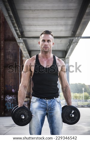 Handsome Hunk Man Lifting Weights Outdoor. Showing Healthy Body While Looking at the Camera.
