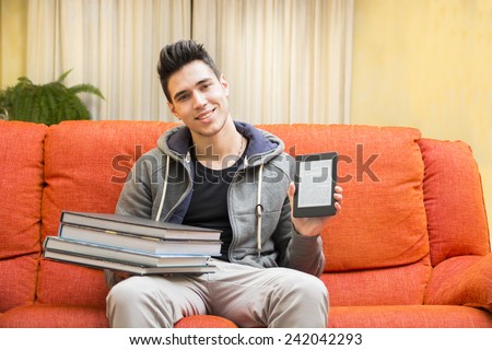Smiling young man showing difference between light and handy ebook reader in one hand and heavy books on other hand