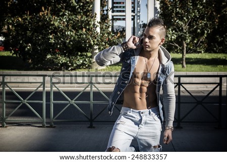Handsome Athletic Man in Denim Fashion Outfit Showing Sexy Six Pack Abs Calling Through Mobile Phone Outdoor.