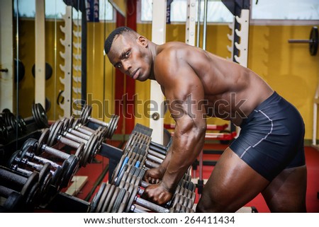 Handsome black male bodybuilder resting after workout in gym, looking at camera
