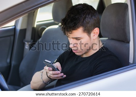 Distracted Handsome Young Man Busy with his Cell Phone While Driving a Car.