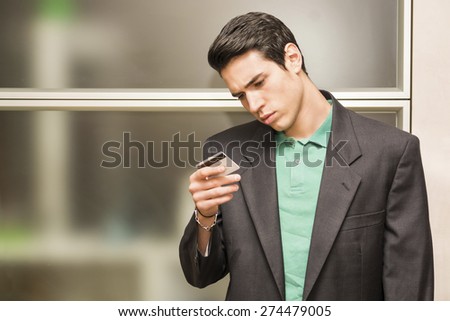 Attractive young business man in office holding and looking at credit card