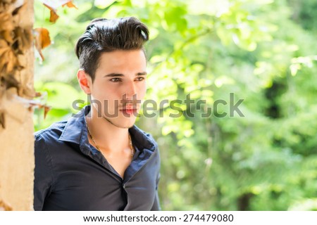 Serious looking  young man wearing black shirt looking outside