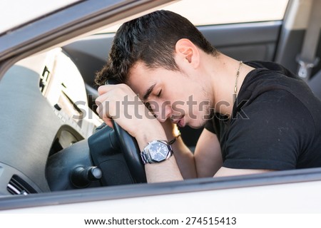 Handsome Young Man sleeping in a Car, resting head on wheel