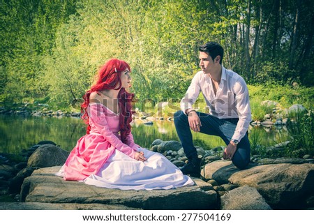 Romantic Fairy Tale Couple Sitting on Rocks at River Side in Peaceful Idyllic Setting, Prince and Princess Gazing at Each Other