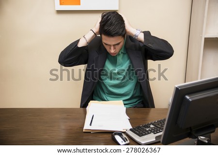 Preoccupied, worried, desperate young male worker staring at computer screen in his office