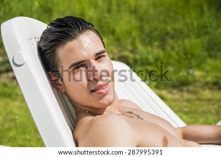 Shirtless Young Man Drying Off in Hot Sun, Muscular Man Wearing Bathing Suit and Sunglasses Sunbathing on Pool Side Lounge Chair on Grass