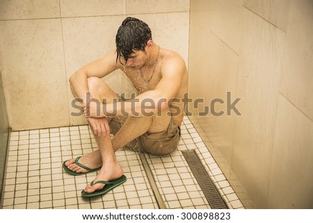 Close up Attractive Young Bare Sad Worried Young Man Taking Shower, Sitting on the Floor with Eyes Closed