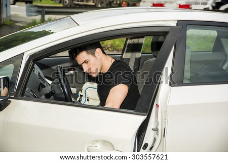 Young attractive man getting out of white car, opening the door