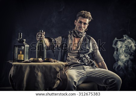 Good Looking Young Man in Pirate Fashion Outfit Sitting next to Table with Candle Lamp, Compass, Gold