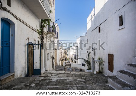Narrow Cobblestone Alley Between White Washed Mediterranean Houses on Hill Side in Ibiza, Spain on Sunny Day with Blue Sky