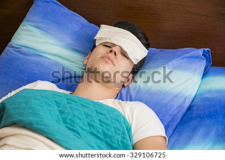 Young handsome sick or unwell man in bed with a flu or fever