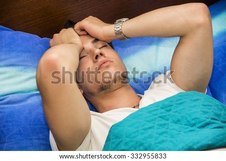 Young Attractive Man Holding Head and Lying in Bed - Close Up of Sick Man with Headache Recuperating in Bed