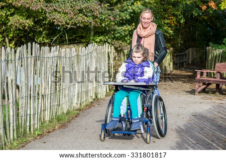 Disabled child in wheelchair with care assistant/ Disabled child in wheelchair