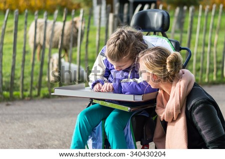 Disabled girl in a wheelchair relaxing outside with animals and the help from a care assistant / Disabled girl relaxing outside