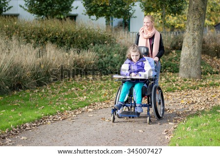 Disabled child in a wheelchair relaxing outside with help from a care assistant / Disabled child in a wheelchair relaxing outside