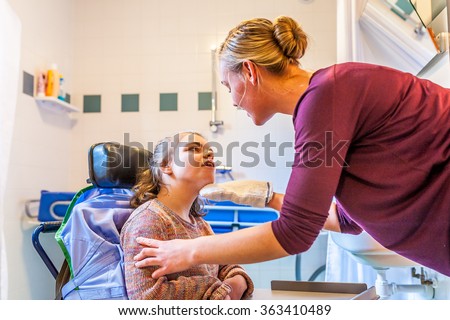 Disabled child in a wheelchair being cared for by a special needs care assistant/ Working with disability
