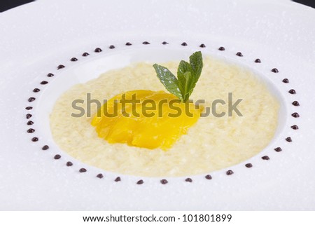 Rice pudding in a white bowl with sliced mango garnish