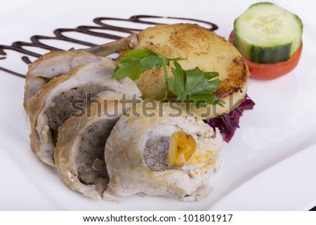 Breast of chicken stuffed with apricot and sage stuffing with a potato cake on a white plate