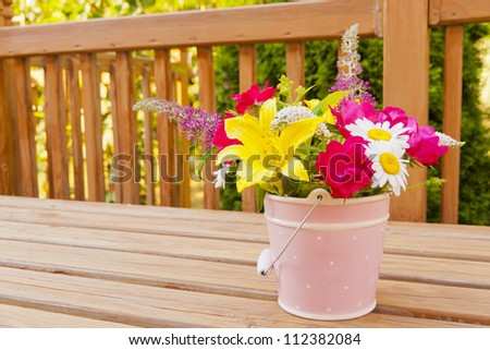 Flowers from the garden in pink bucket vase