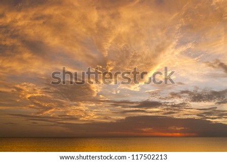 Dramatic sunset sky with clouds over ocean.